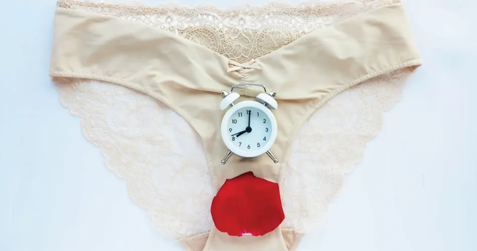 female under wear with rose petal and stop watch on top