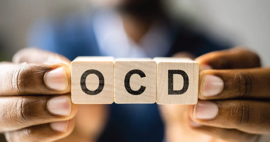 Hands holding wooden cubes spelling "OCD"